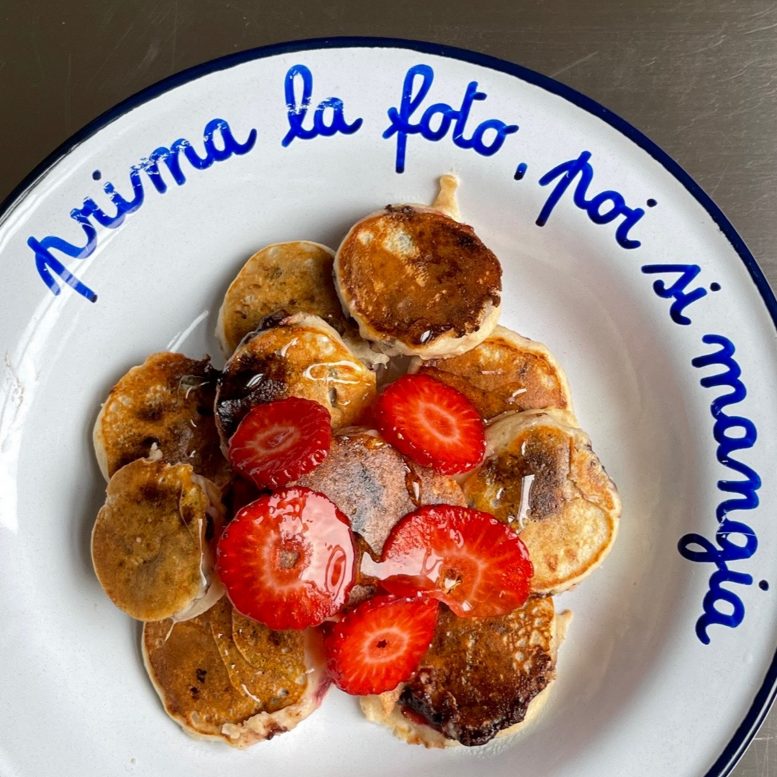 Piatto con scritta "prima la foto, poi si mangia" con mini pancake e fragole