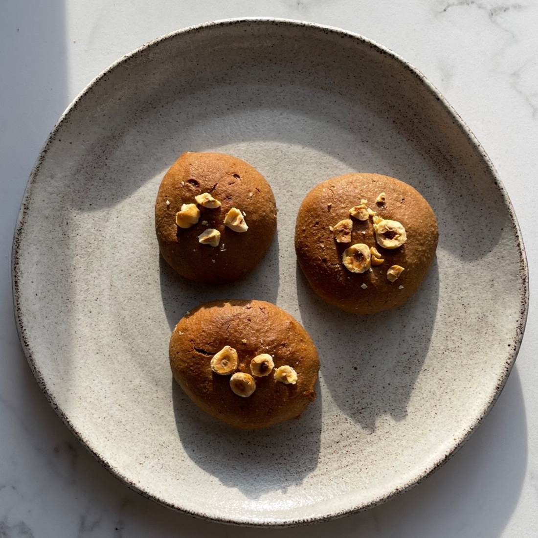 Piatto con tre biscotti brownie vegani con sopra le nocciole