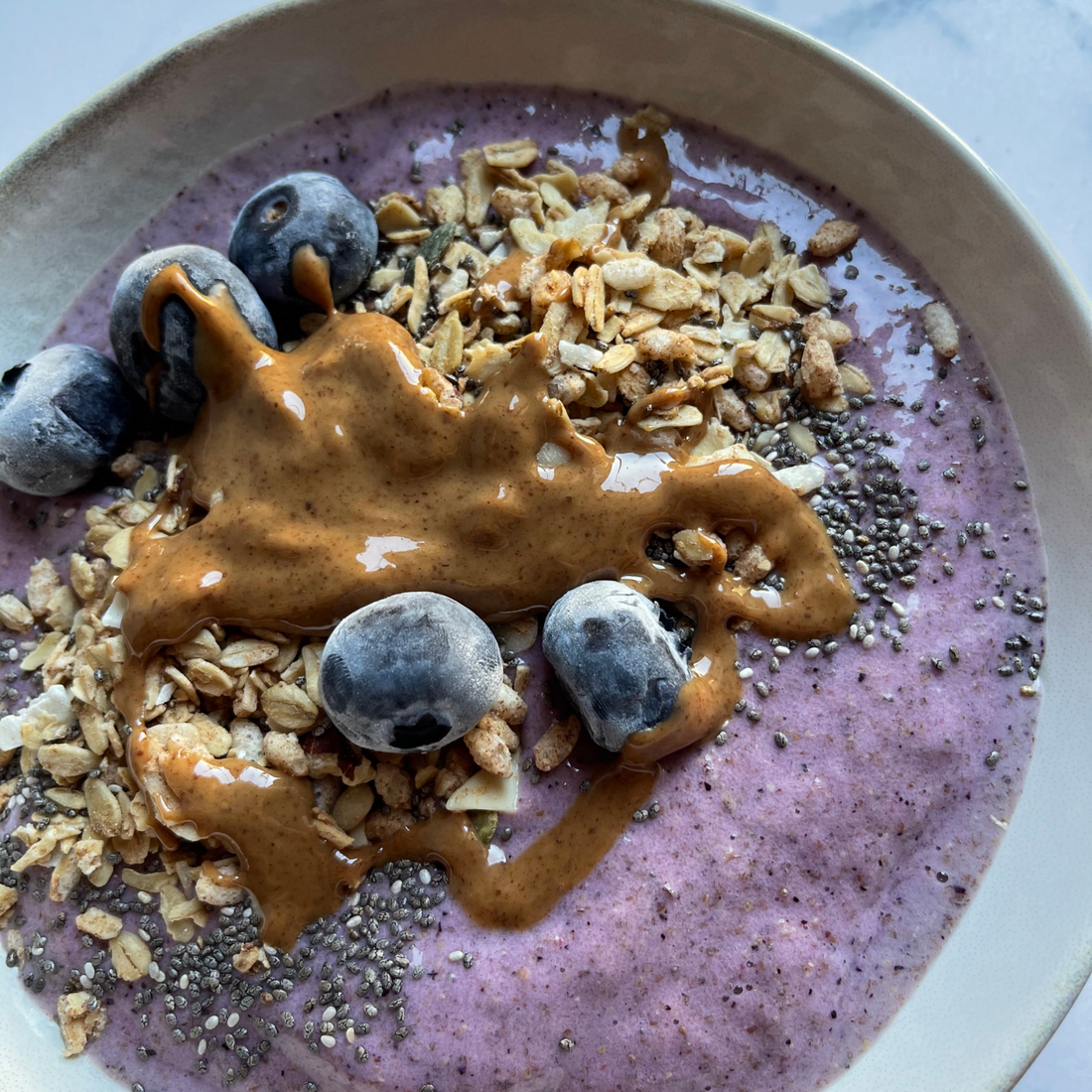 Ciotola con smoothie bowl ai frutti di bosco con semi, mirtilli e burro di arachidi zoommata