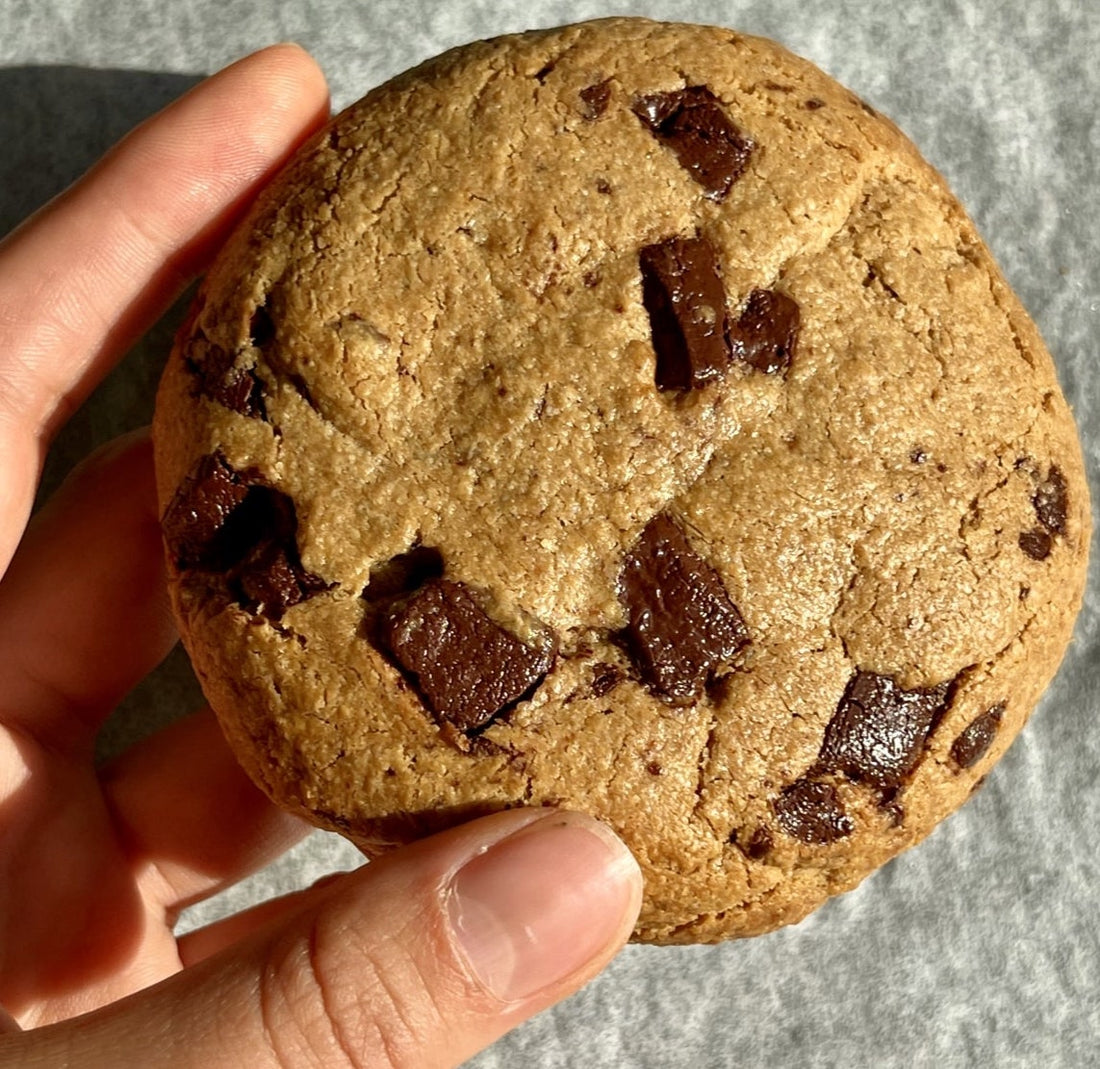 Mano che tiene un single size cookie con sfondo su teglia da forno